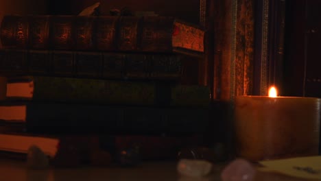 close up background of an ancient library, next to a frieplace, with old books, old paper, stones, and a candle with flickering flame, with some dust flying around