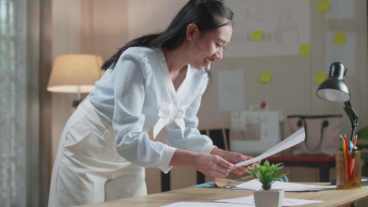 아시아 여성 디자이너가 사무실의 테이블 위에 레이아웃을 배치하고 있습니다.