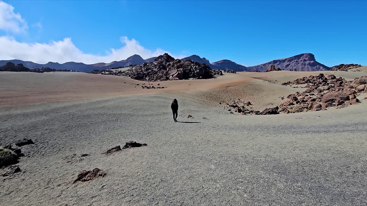 Lonely traveler walking on the sandy terrain of Roques de Garcia, Spain
