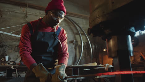 african american blacksmith using hydraulic forging press in workshop