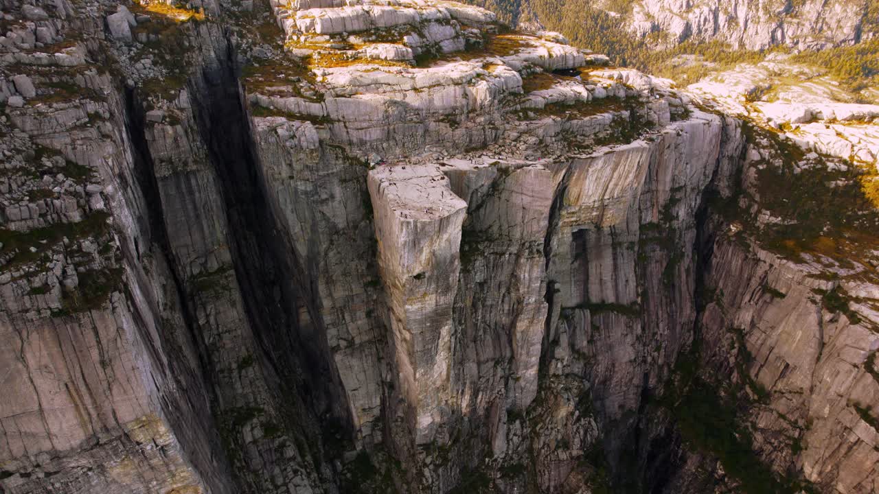 Drone view of the Preikestolen plateau in Norway with tourists enjoying a scenic fjord backdrop.