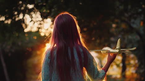 silhouette of a girl with a toy plane playing in the setting sun on the street