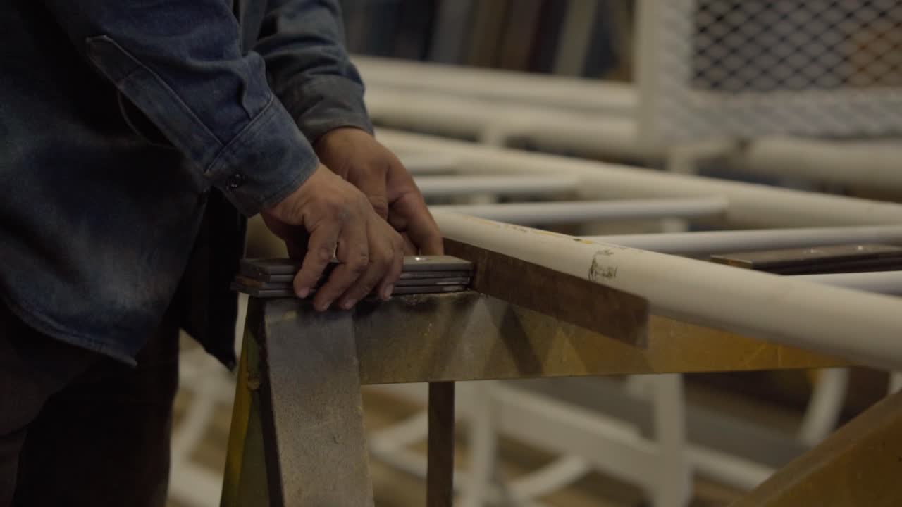 Welder's Hand Holding A Metal Pieces In The Workshop. - closeup shot