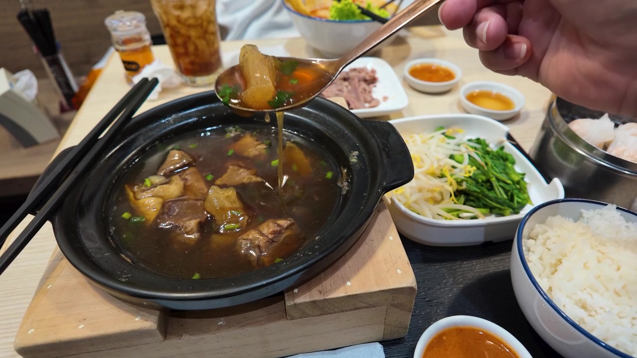 Close-up tangan menyendok sup daging sapi kental dari panci tanah liat di Bangkok.