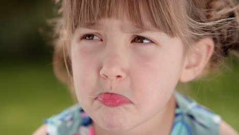 Retrato-De-Una-Linda-Niña-Haciendo-Muecas-Que-Parecen-Un-Niño-Triste-Y-Travieso-Haciendo-Expresiones-Tontas-En-Un-Parque-Soleado-4k