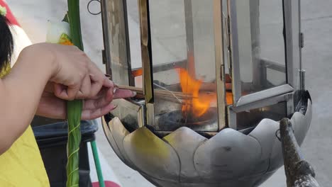 woman lighting incense at a temple