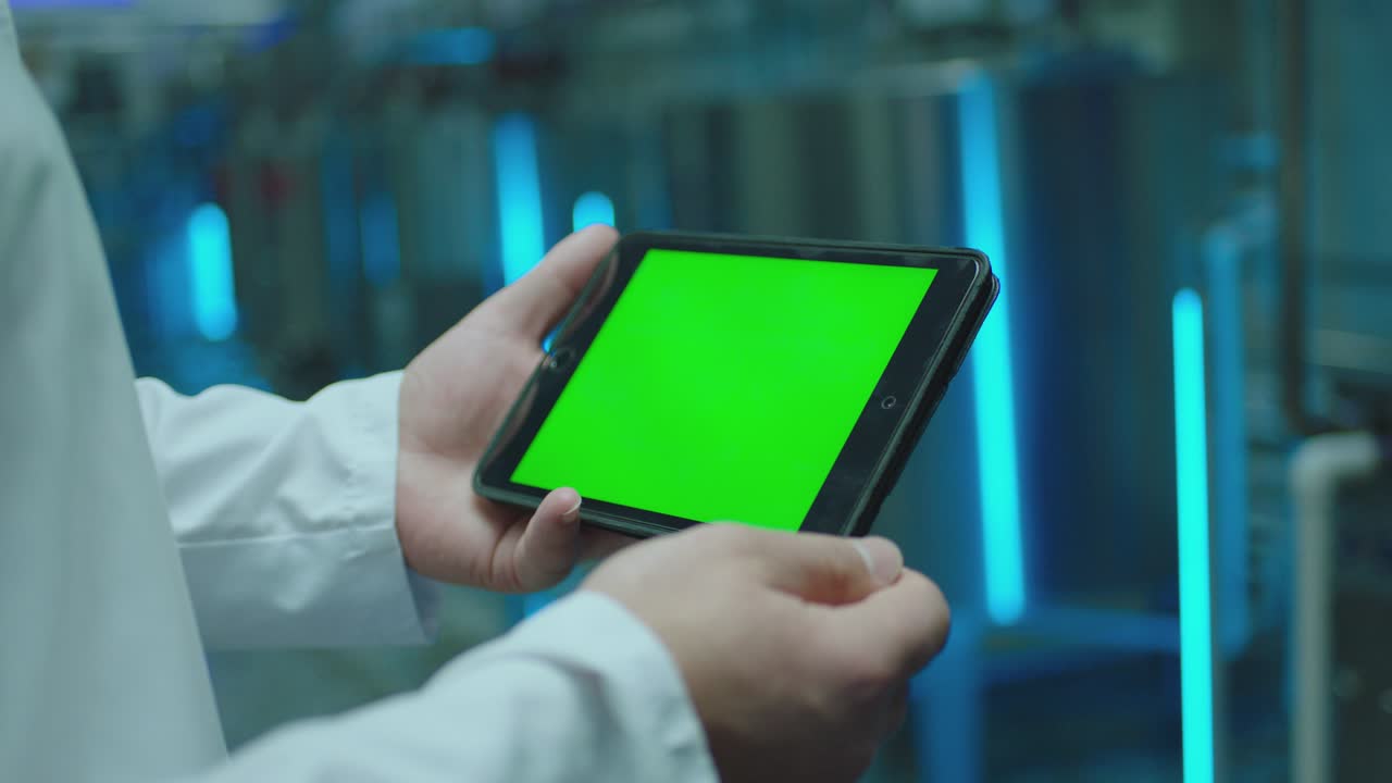 4K Male artist using black tablet with green screen or chroma key screen and doing notes in slow motion .  Close up man's hand  touching gadget screen inside factory or laboratory  .  Working process