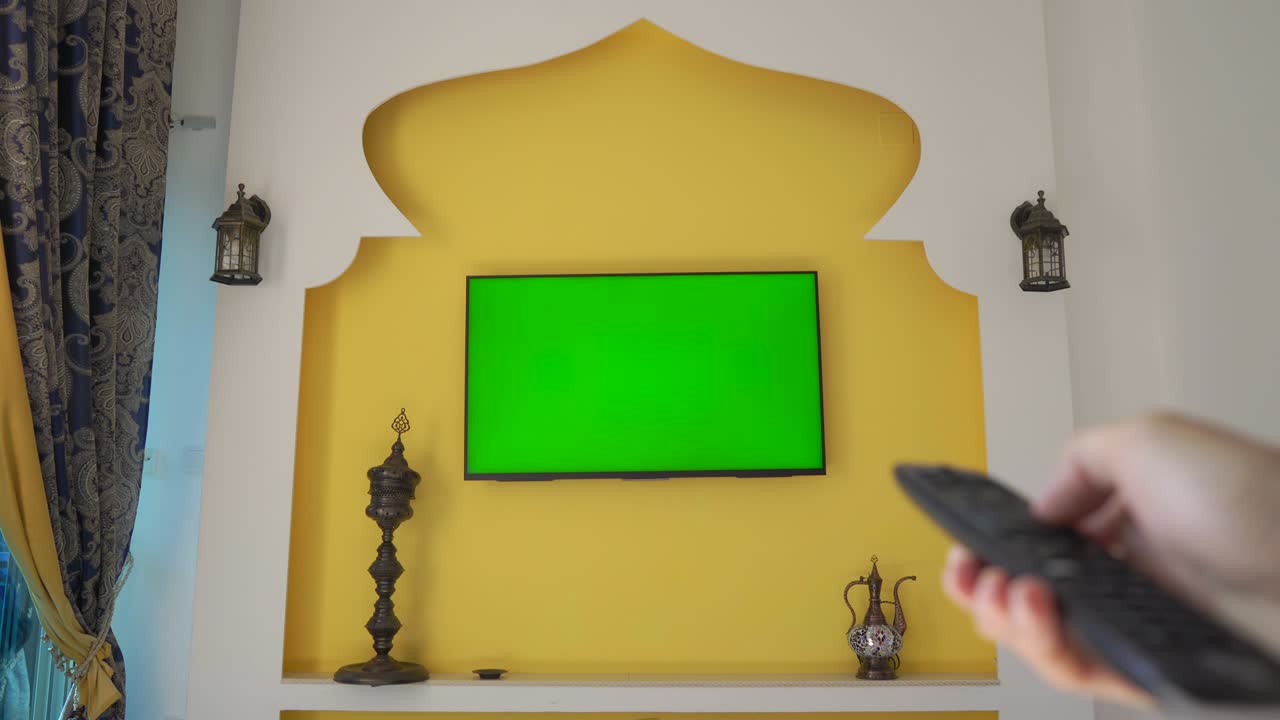 pared con televisión y pantalla verde al estilo de oriente medio y áfrica del norte. mano con control remoto. copa árabe en qatar