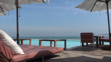 chair-and-umbrella-with-swimming-pool-and-sea-beach-background