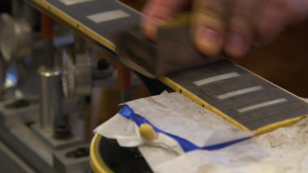 Close up ebony fretboard on electric guitar sanded by technician