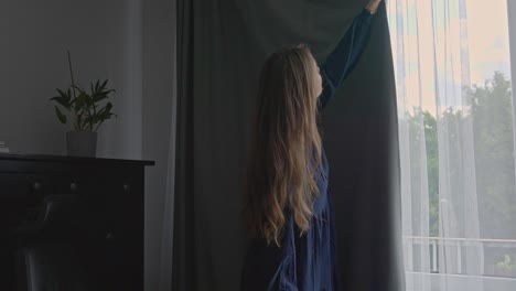 woman in bright home office closing grey window curtain, stable shot