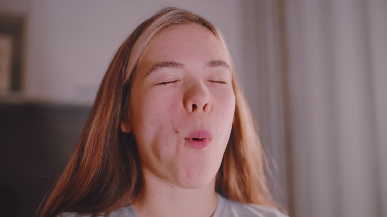 Close up of freelancer savoring sandwich with thoughtful expression, hands holding bread layered with cucumber and meat, natural indoor lighting highlighting relaxed eating