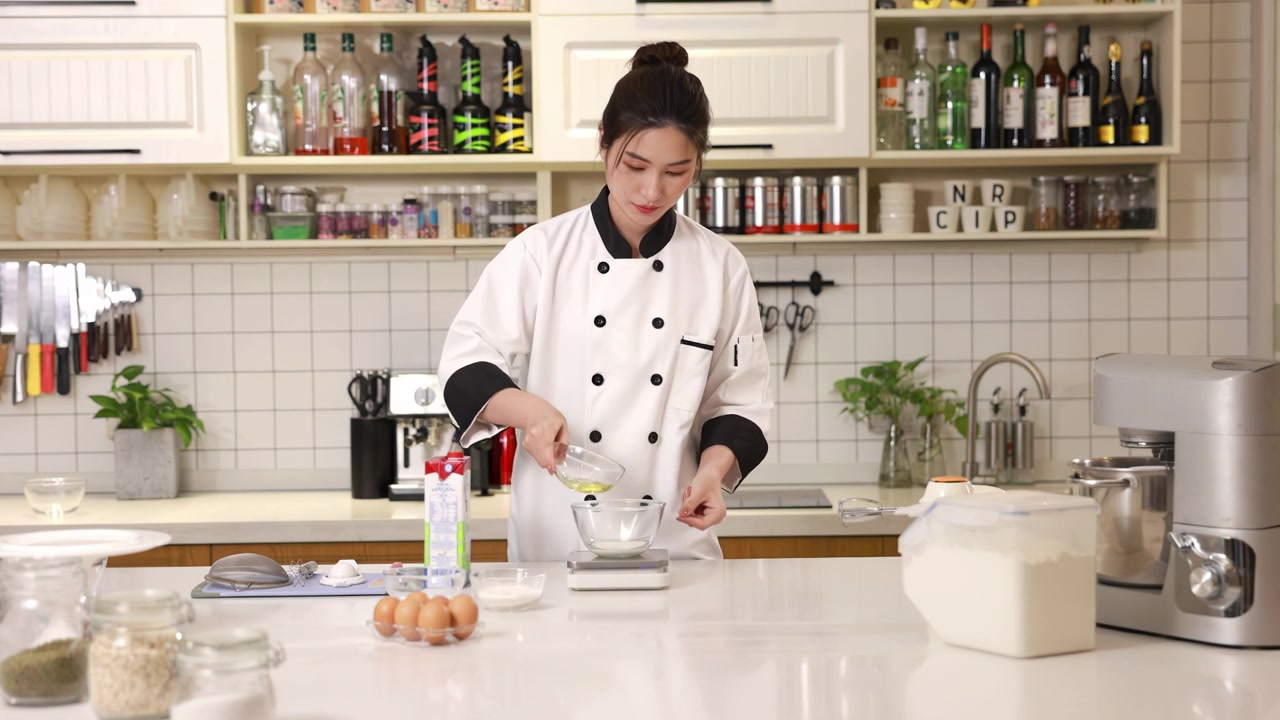 Koki kue/roti menuangkan susu krim segar, minyak goreng ke dalam mangkuk kaca putih untuk menimbangnya, menyiapkan bahan-bahan untuk hidangan penutup, persiapan adonan untuk memanggang kue atau roti di dapur modern.
