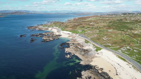 Drone-shot-of-Coral-Beach-in-Ballyconneely,-aerial-footage-or-road-on-coastline-and-clear-ocean-waters
