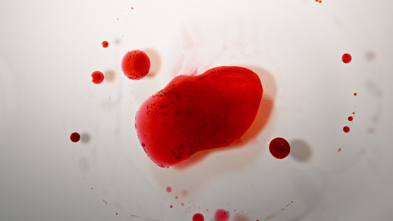 Ink mixing in macro shot with vivid red and black ink drops on a white surface