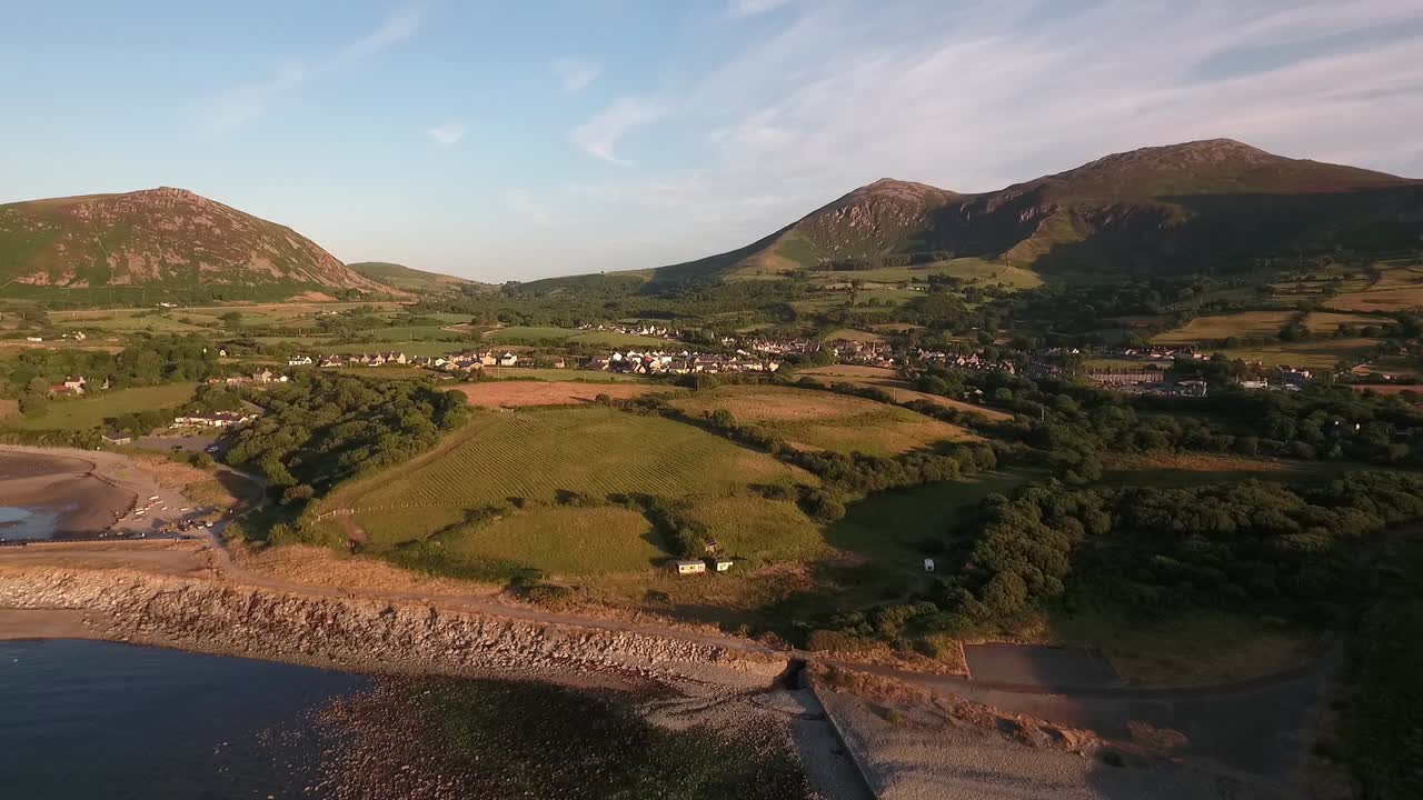 acercamiento aéreo al puerto y al pueblo de trefor sobre la playa y el muelle con cielos azules en un día de verano a través del mar de irlanda en la península de illyn en el norte de gales