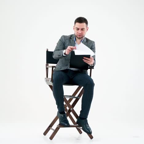 elegant man with a folder. businessman sitting on the chair and reading documents. many papers are flying in the studio over the handsome man.