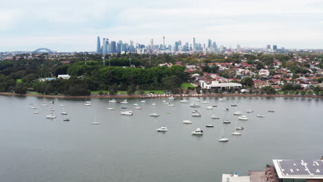 Aerial-drone-shot-flying-over-the-Parramatta-river-with-the-Sydney-skyline-in-the-distance,-Australia