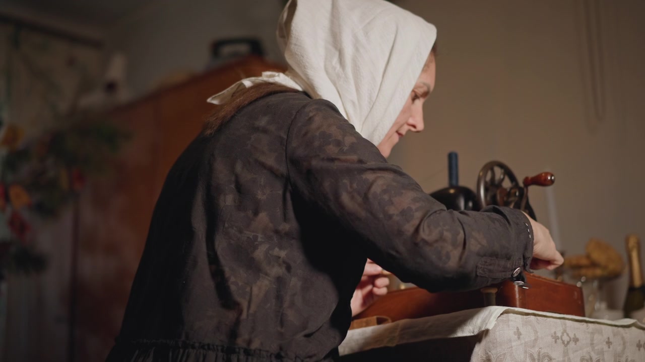 Iäkäs nainen korjaa. Kokenut käsityöläinen korjaa kärsivällisesti arvokkaita vaatteita rauhassa. Kokenut artesaani entisöi huolellisesti vintage-vaatteita tarkkaavaisesti ja hiljaisella omistautumisella.