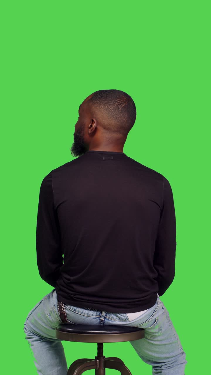 Vertical video: Back view of young happy person on chair sitting and waiting
