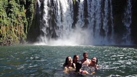friends swimming at waterfall