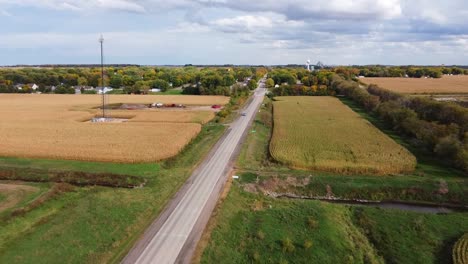 aerial view of a highway surrounded by cornfields and a cellphone tower in the midwest during the autumn season