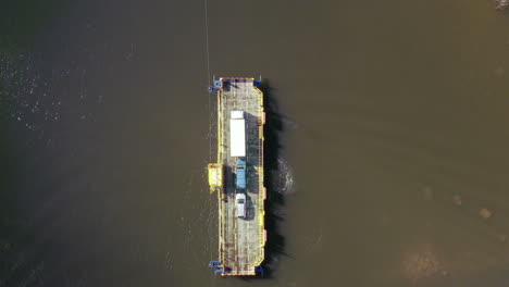 aerial view panning away from a cable ferry in the archipelago of porvoo, sunny, spring day, in uusimaa, finland - top down, drone shot