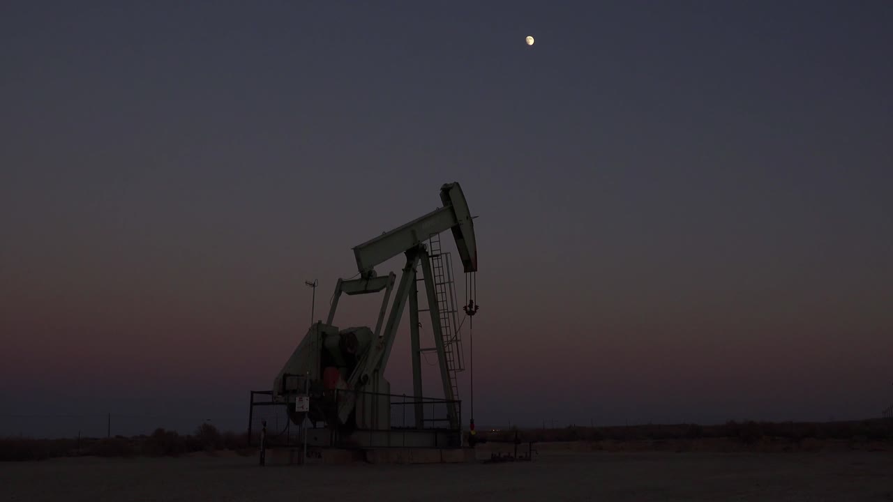 una torre de perforación de petróleo bombea contra el cielo nocturno