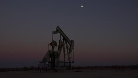 an oil derrick pumps against the night sky