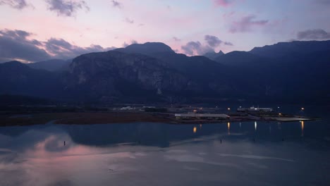 aerial-zoom-in-Squamish-Spit-river-conservation-area-with-natural-scenic-mountains-landscape-colourful-sunset-with-illuminated-harbour