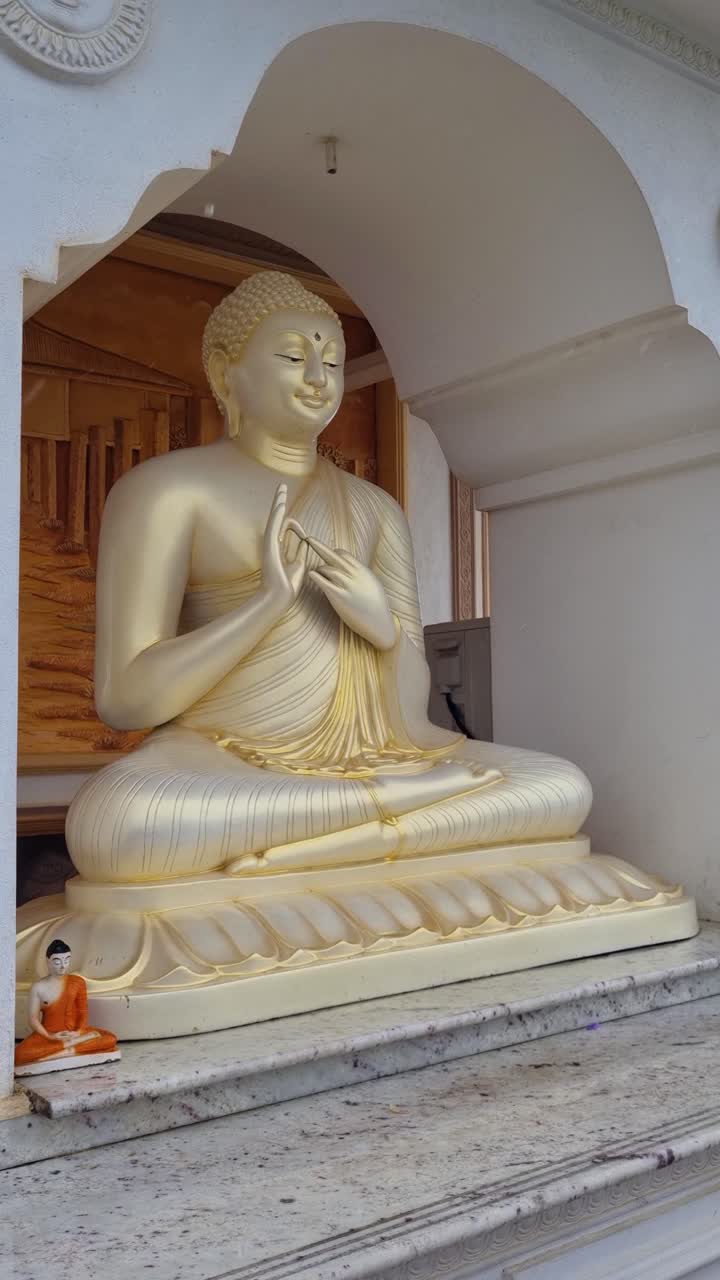 Scatto verticale di una statua di Buddha al tempio Parewi Duwa a Matara, nello Sri Lanka, con la pioggia che cade, evidenziando l'atmosfera serena e l'ambiente spirituale e tropicale del tempio