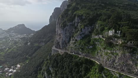 Un-Camino-Serpenteante-A-Lo-Largo-Del-Acantilado-De-Capri,-Italia-Con-Exuberante-Vegetación,-Vista-Aérea