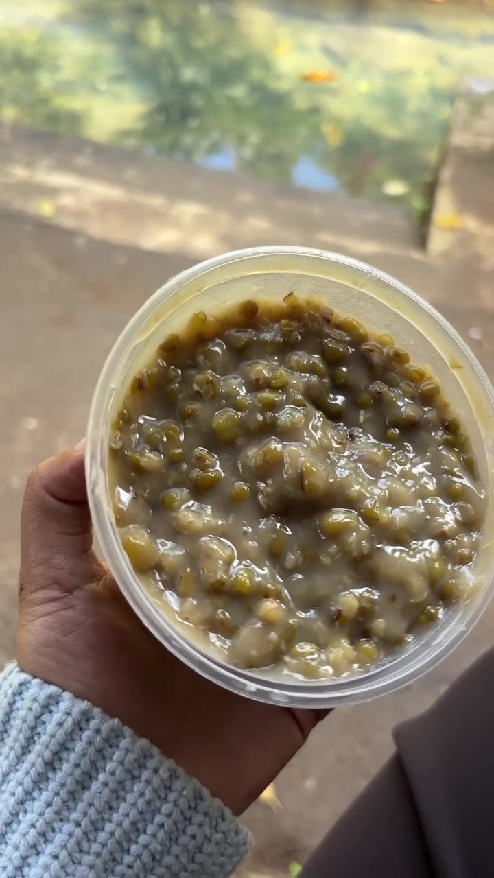 Hand Holding a Plastic Container of Mung Bean Porridge
