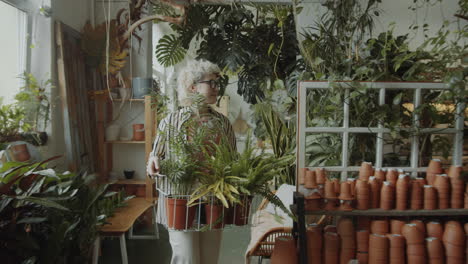 female florist walking with plants in flower store