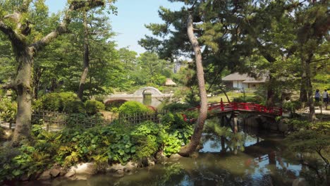 japanese garden shukkei-en in hiroshima, with a pond and a red bridge in may