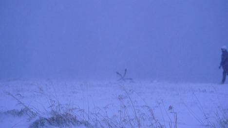 lonely woman walking slow mo in heavy windy snowstorm, stable shot