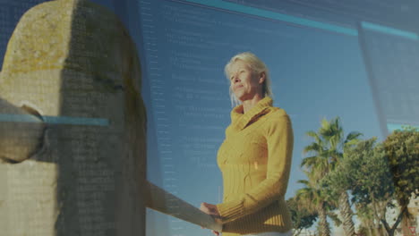 elderly woman in yellow sweater reading outdoors with code overlay animation