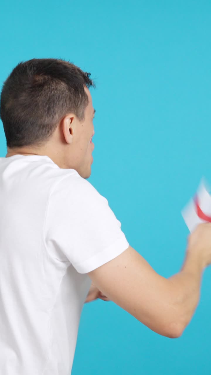 Rear view of a man waving a english pennant