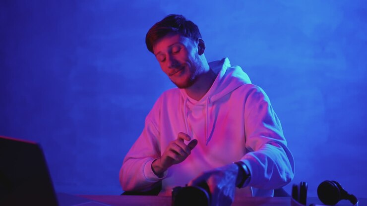 Man working with a computer and a professional photo camera on a colorful neon light background