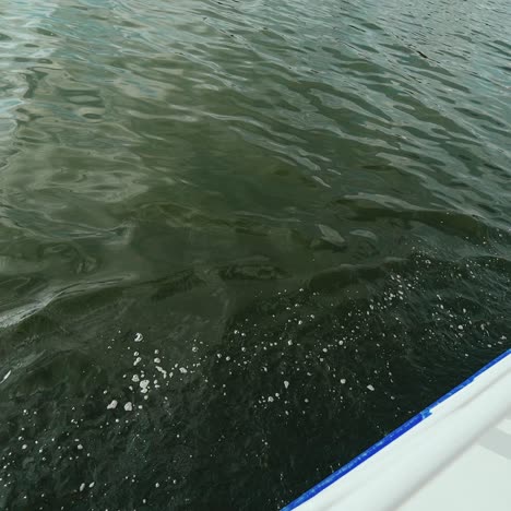 sailing boat cuts through waves in a river.