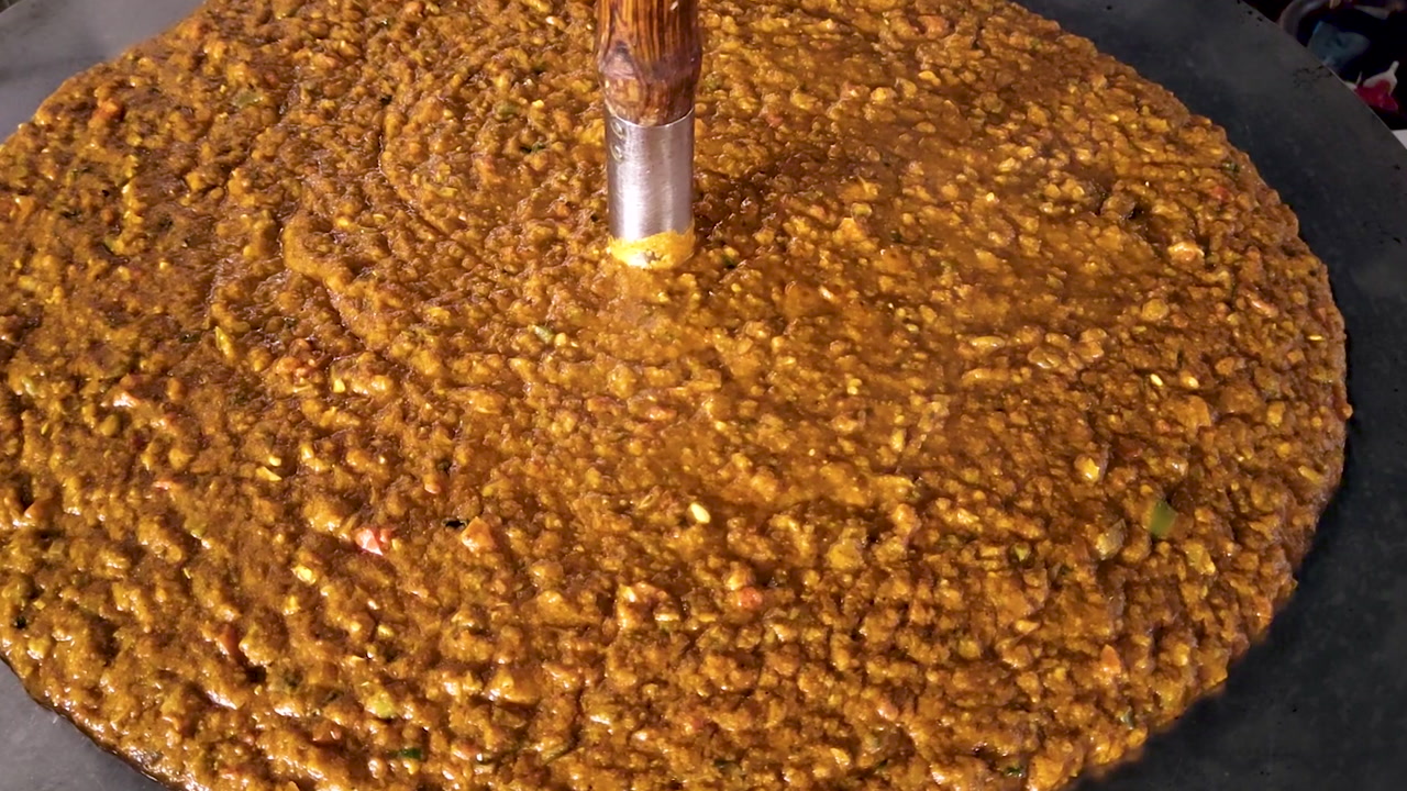 Pav-bhaji being prepared on large hot griddle, mixed vegetable curry, vibrant spices, street food cooking, close-up of stirring and sizzling, Indian food culture