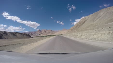 driving through ladakh region in india. arid landscape with mountains and sand