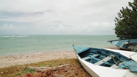 man sitting on a abandoned boat on the beach shoreline in tobago, west indies