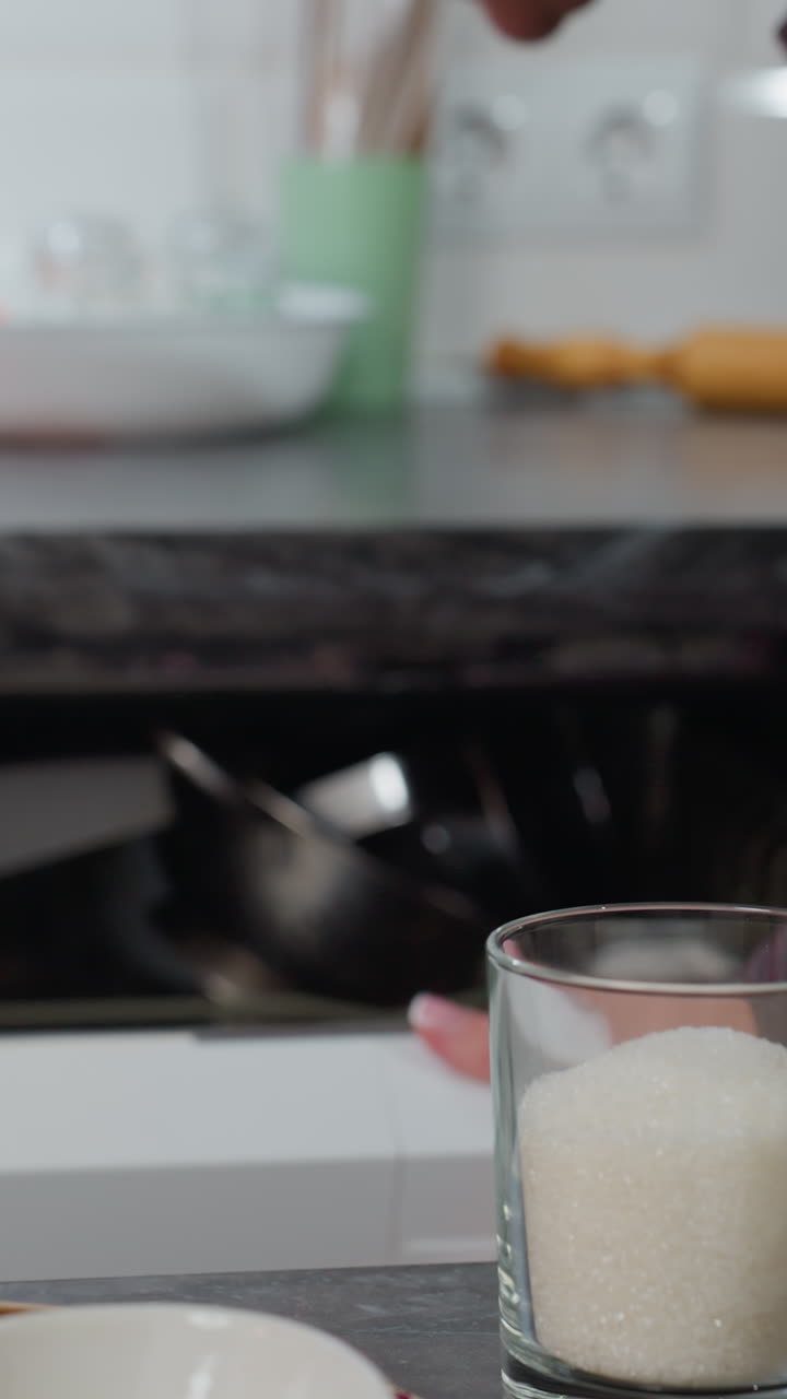 частичный вид человека, удаляющего кастрюлю из электрической печи, помещающего ее обратно в открытый кухонный шкаф с аккуратно расположенным кухонным оборудованием, столовой свечи, горящей на переднем плане