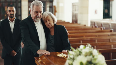 Funeral,-coffin-and-senior-couple-hug-in-church