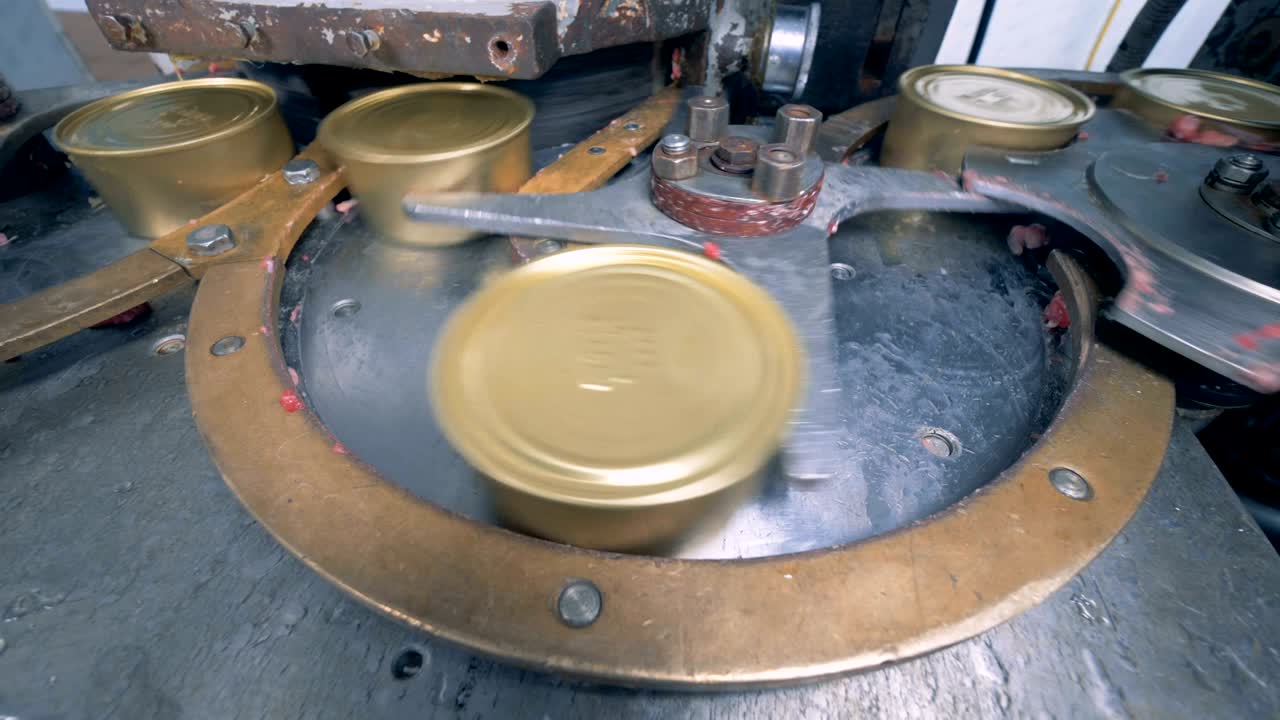 준비된 라벨이 붙지 않은 고기 캔이 컨베이어 섹션을 돌아다니고 있습니다.