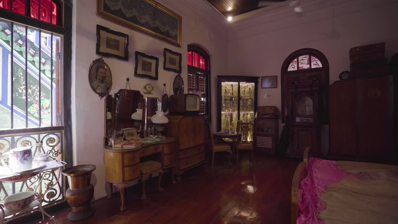 Vintage Furniture And Appliances Displayed Inside The Bedroom In Pinang Peranakan Mansion In Penang, Malaysia With Shadow Of Rotating Ceiling Fan On The Wall - Panoramic Shot