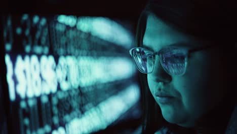 primer plano de una mujer adulta joven con gafas reflectantes que analiza el código de datos de seguridad cibernética trabajando de noche concentrando pantallas de ordenador | criptomoneda virus financiero hacker mujeres programador 4k