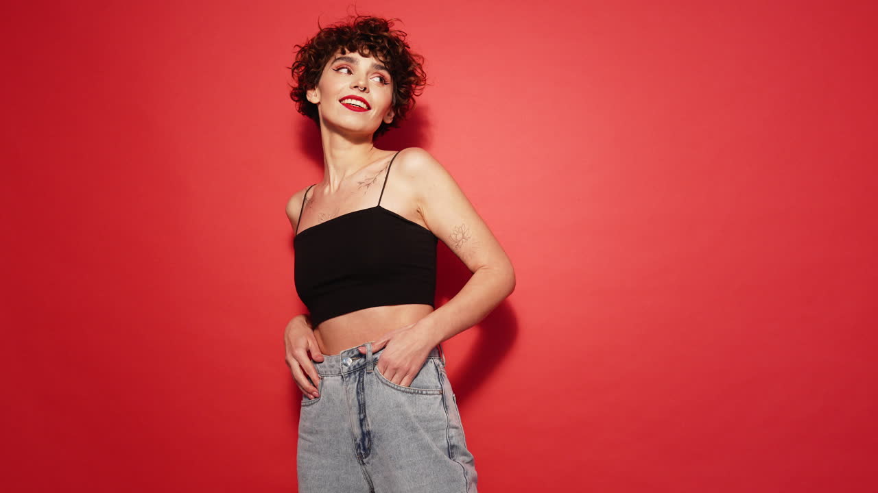 mujer elegante en vaqueros y crop top contra fondo rojo