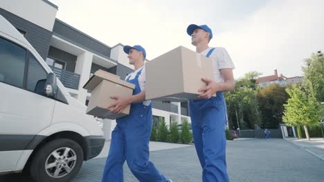 two young workers of removal company are loading boxes and furniture into a minibus